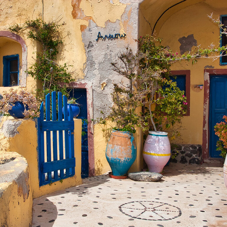 Yellow peeling paint and blue gate and door in a tiled courtyard.