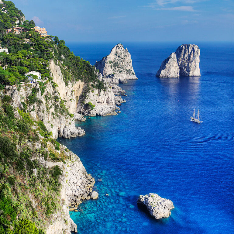Blue water of Capri with a sailboat.