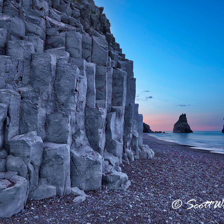 Basalt columns on a black beach at sunrise.