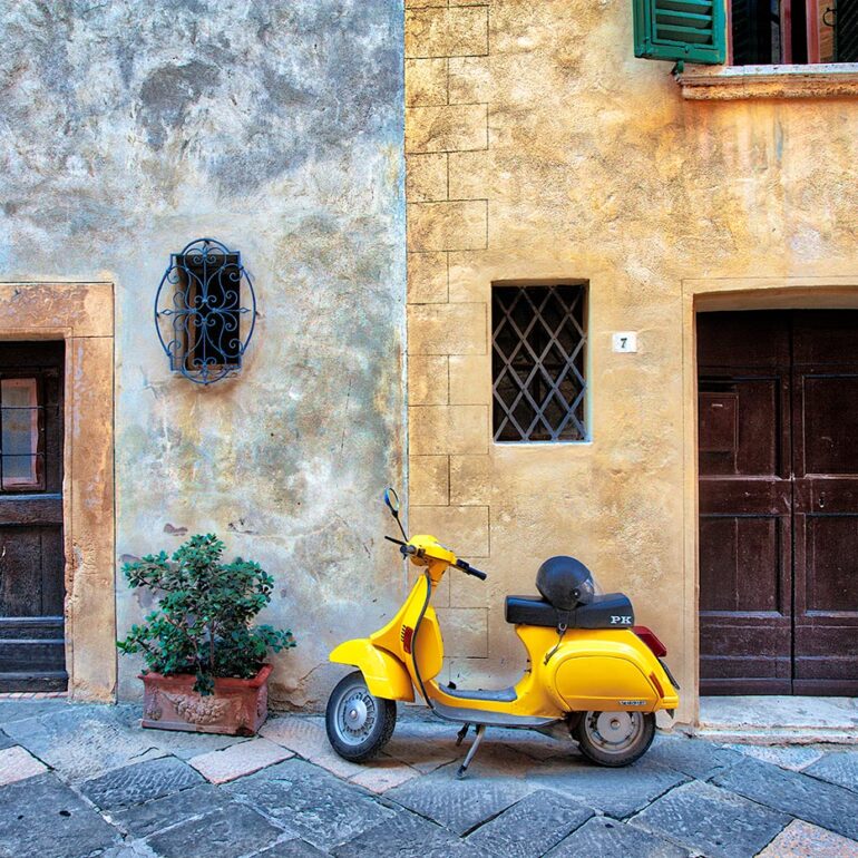 Yellow scooter against and old wall.