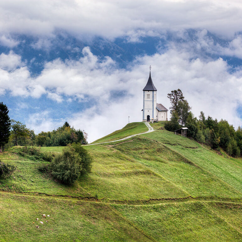 Church set at the top of a hill shrouded in clouds.