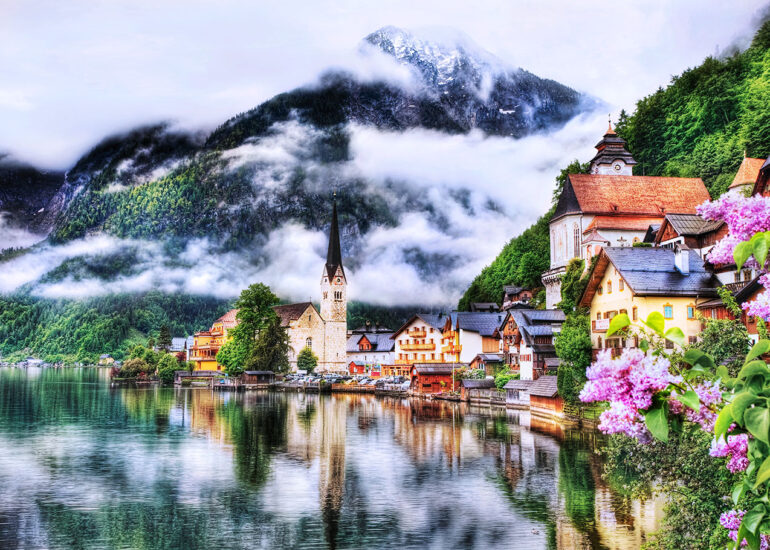 Church set on the water along a lake in front of a mountain on a misty morning.