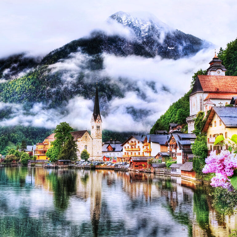 Church set on the water along a lake in front of a mountain on a misty morning.
