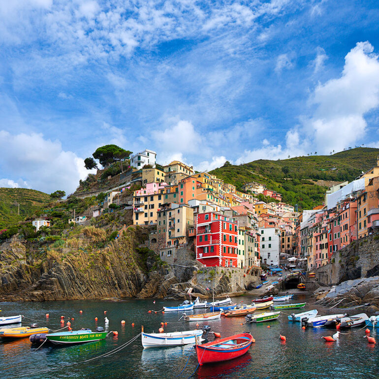 The harbor of Riomaggiore with boats and painted buildings.