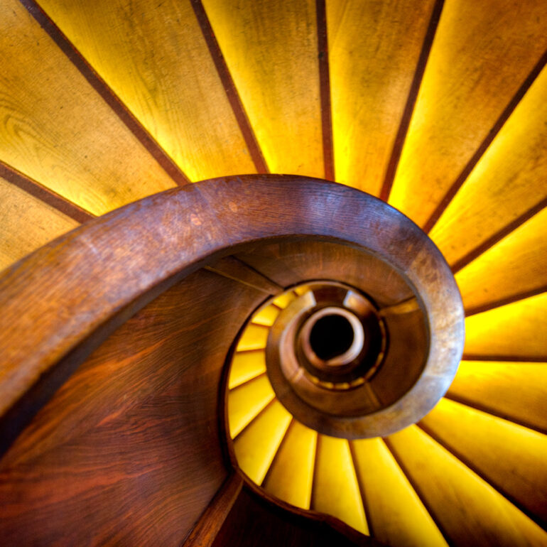 Old wooden spiral staircase going down.